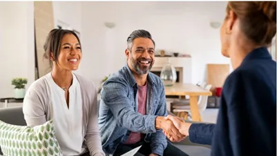 Two individuals shaking hands with a financial adviser